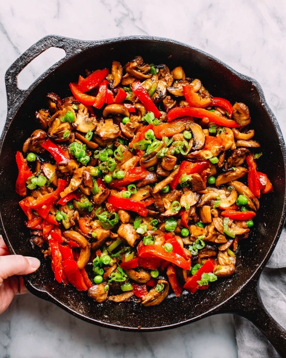 The image shows a cast iron skillet filled with a colorful stir-fry mix. It has roughly chopped pieces of brown mushrooms and bright red bell peppers, scattered with small green peas. The ingredients look cooked but still fresh, with a slight shine from oil. The skillet sits on a white marbled surface, and a woman's hand is holding one handle of the skillet at the top right corner. Photo taken with an iphone --ar 4:5 --v 7