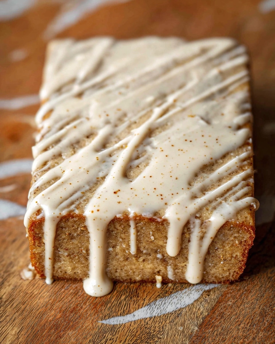 A close-up view of a single rectangular piece of light brown cake with a rough texture, sitting on a wooden surface with a white marbled texture replaced underneath. The cake is covered unevenly with light beige creamy glaze drizzled across the top in thick and thin lines, some of which are dripping down the sides to the surface below. The glaze has tiny brown specks visible throughout, adding a bit of texture to the smooth cream layer. Photo taken with an iphone --ar 4:5 --v 7