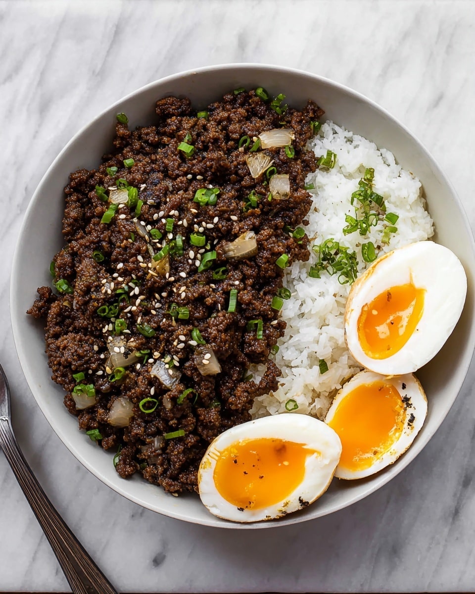 In a white bowl on a white marbled surface, there is a dish with three parts: on the left side, there is a large portion of dark brown cooked ground meat mixed with small pieces of onions, sprinkled with green chopped herbs and white sesame seeds; on the right side, there is a scoop of steamed white rice with a few green herb bits; placed next to the rice are two halves of a soft-boiled egg with firm white outer layers and bright yellow-orange runny yolks. Photo taken with an iphone --ar 4:5 --v 7