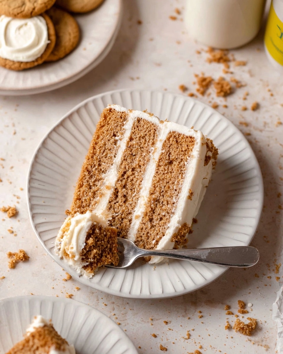 A slice of three-layer light brown cake with smooth white frosting between each layer and on the outside sits on a white plate with a ridged edge. A fork resting on the plate holds a piece of the cake with visible crumbs. In the top left corner, there are two round cookies with white filling, and crumbs are scattered around on a white marbled surface. Part of another white plate with a similar slice of cake is seen in the bottom left corner. photo taken with an iphone --ar 4:5 --v 7