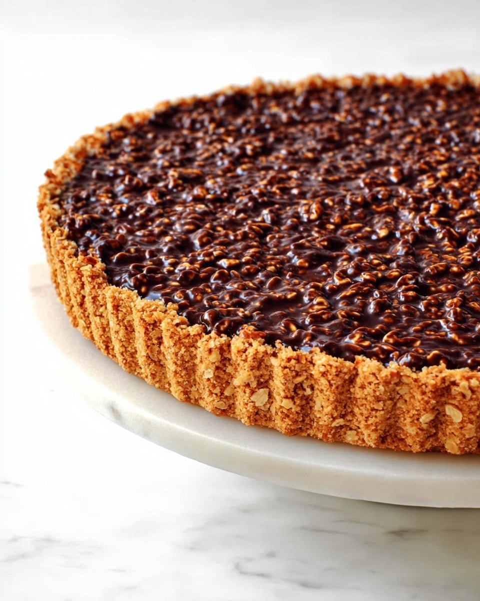 A close-up image of a two-layer dessert tart resting on a white marbled surface, with the tart placed on a white cake stand. The bottom layer is a thick, crumbly golden-brown crust that forms the sides and base, textured with visible crumbs and ridges. The top layer is a dense, uneven surface of dark chocolate mixed with puffed rice or similar crunchy bits, creating a bumpy texture with glossy spots. The tart is shown from a side angle to highlight the contrast between the crumbly crust and the glossy chocolate topping. Photo taken with an iphone --ar 4:5 --v 7
