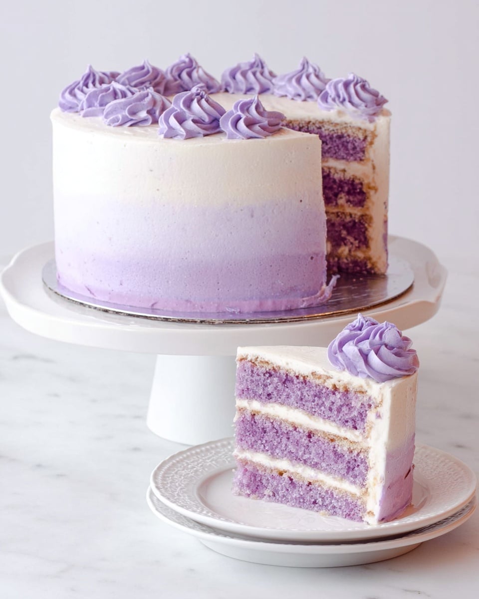 The image shows a two-layer cake with light purple sponge layers separated by thin white cream filling. The outside is covered in smooth white frosting with a gradient effect transitioning to light purple around the bottom edge. The top is decorated with small swirls of purple frosting evenly spaced across the surface. A slice of the cake is plated on a white plate in the foreground, showing the purple sponge and cream layers inside. The cake sits on a white cake stand with a smooth, shiny metallic top, all placed on a white marbled surface. photo taken with an iphone --ar 4:5 --v 7