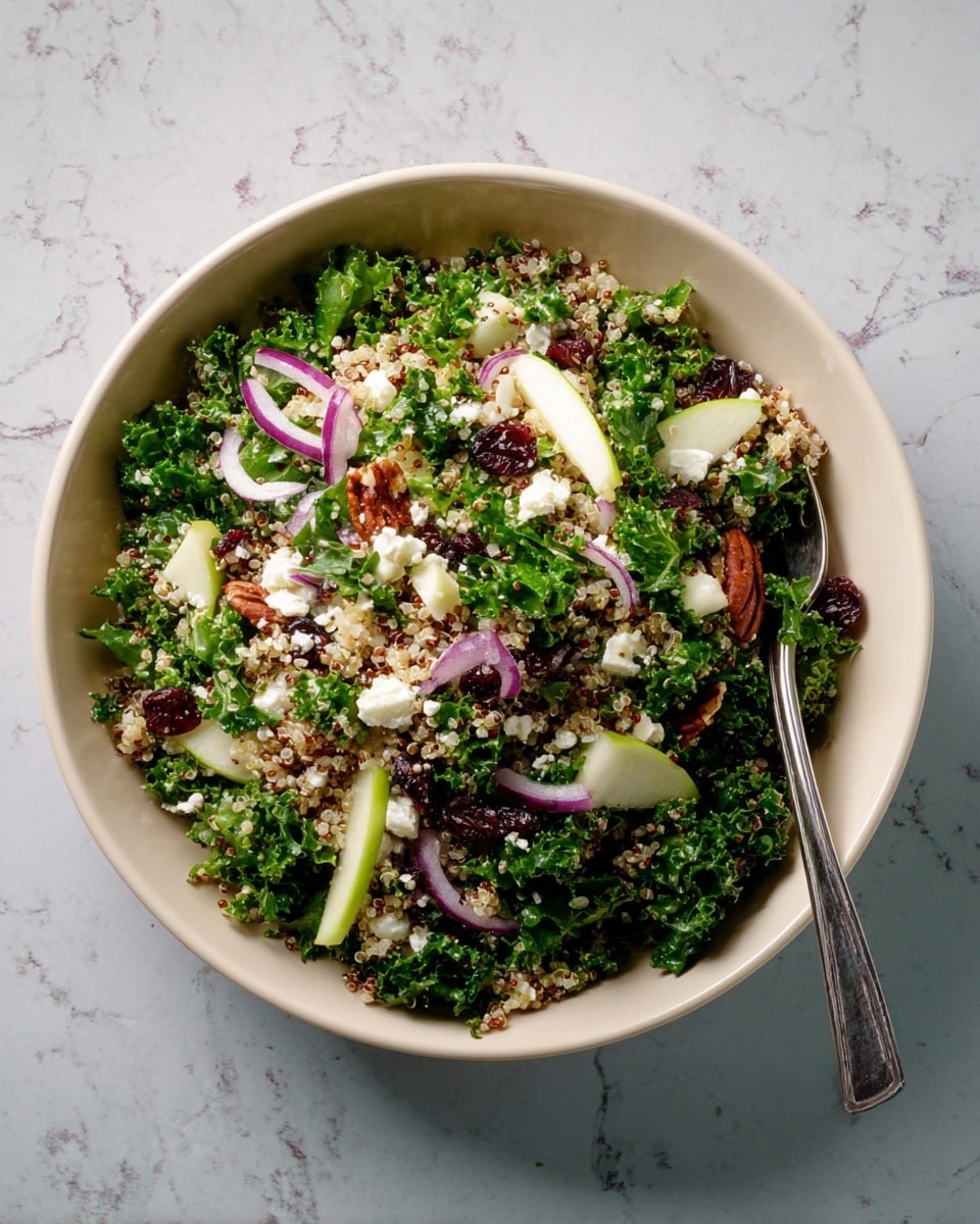 A white bowl filled with a fresh salad showing multiple layers: the bottom layer is green leafy kale, topped with a mix of light beige quinoa grains, light green apple chunks, and thin slices of purple onion. Scattered throughout are small white crumbles of cheese and dark red dried cranberries, with a few brown pecans adding texture. A silver fork rests inside the bowl on the right side, all placed on a white marbled surface. Photo taken with an iphone --ar 4:5 --v 7