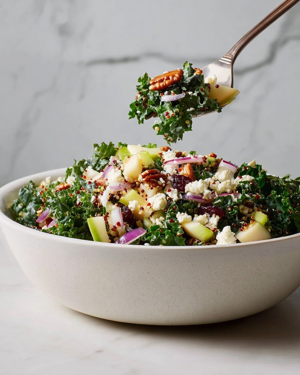 A large white bowl is filled with a colorful salad made of several layers: the base is dark green curly kale leaves, topped with small white crumbles of cheese, light green diced apple pieces, thin slices of purple onion, and reddish-brown pecans scattered throughout, with some tiny quinoa grains adding texture. A fork is lifting a bite that shows a mix of kale, apple, cheese, and pecan. The background is a white marbled texture. photo taken with an iphone --ar 4:5 --v 7