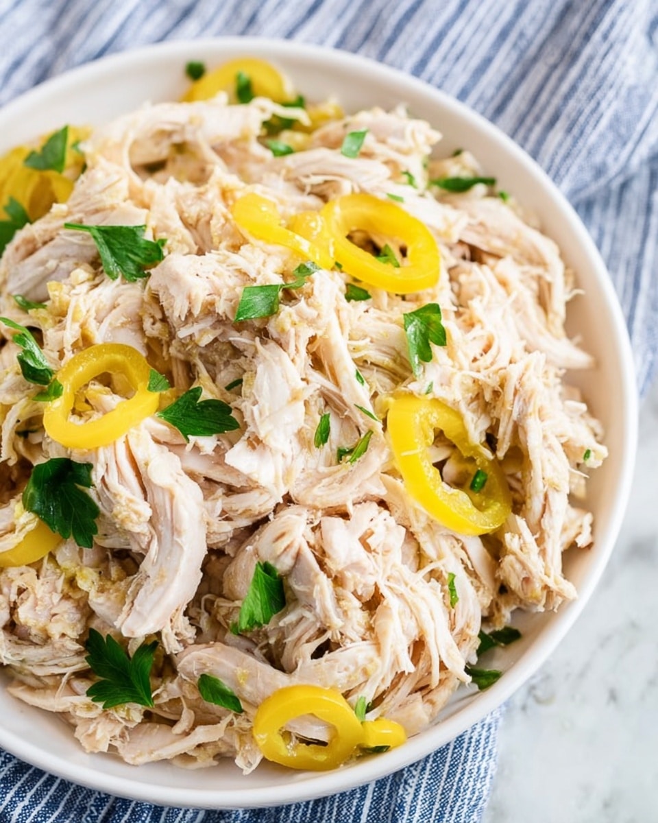 The image shows a single layer of shredded cooked chicken with a light beige color mixed with small pieces of darker brown chicken in a black slow cooker. On top of the chicken, there are five whole greenish-yellow pepperoncini peppers scattered evenly, adding a bright contrast. The texture of the chicken looks tender and moist, and the surface around it inside the cooker is slightly glossy from juices. The setting is on a white marbled texture surface. photo taken with an iphone --ar 4:5 --v 7
